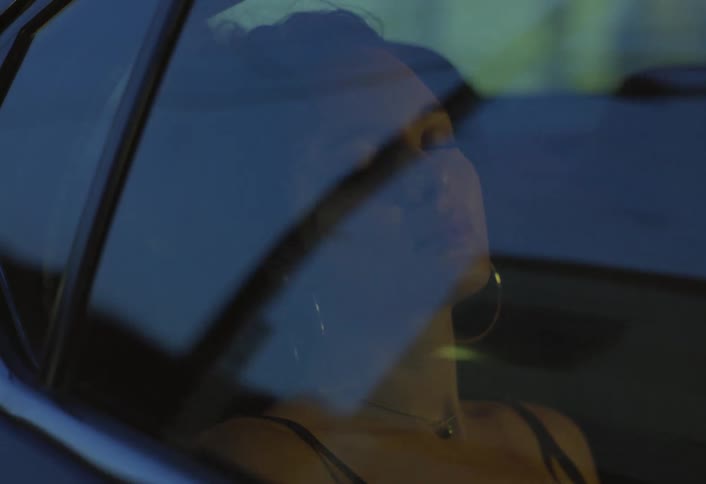 Woman rests with her eyes closed leaning against the car window