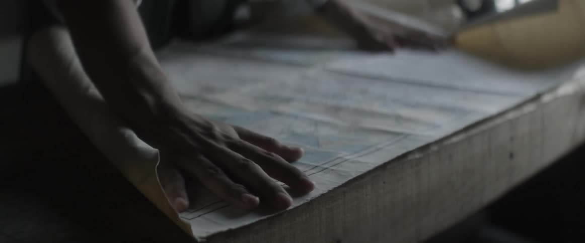 A person rolling out plans on a table