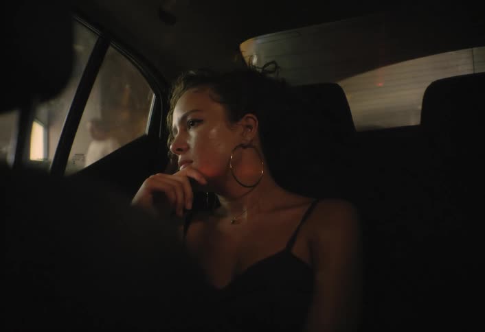 A woman is sitting in a car as it moves in a parking garage
