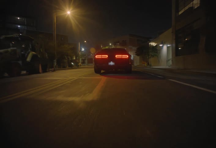 Car moves along city streets at night passing under a bridge