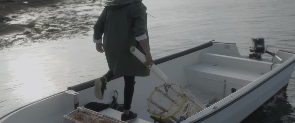 Man holding rolled up map getting into small boat