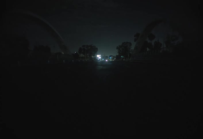 Nearly empty street lit by distant headlights at night