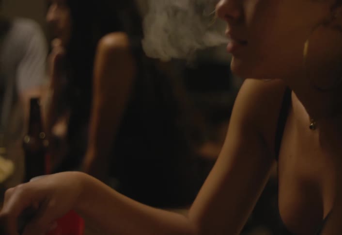 Woman smoking and interacting with a beer bottle on a wooden table