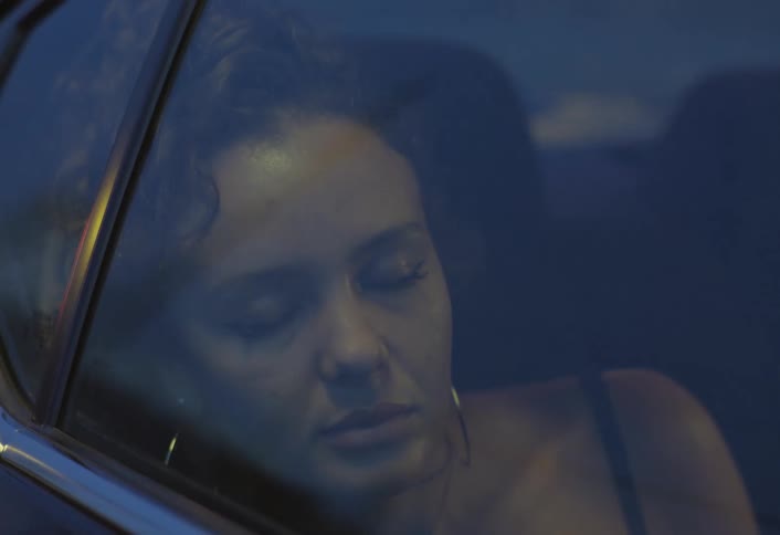 A young woman sitting in the back seat of a car enjoys her ride while sleeping