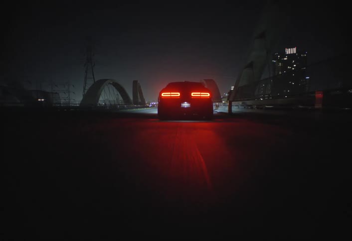 Two vehicles cross a bridge located near downtown at night