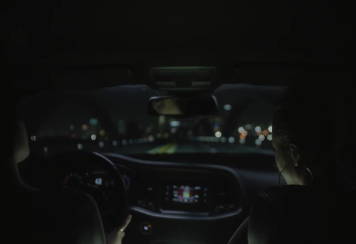 Two women talking inside a car at night