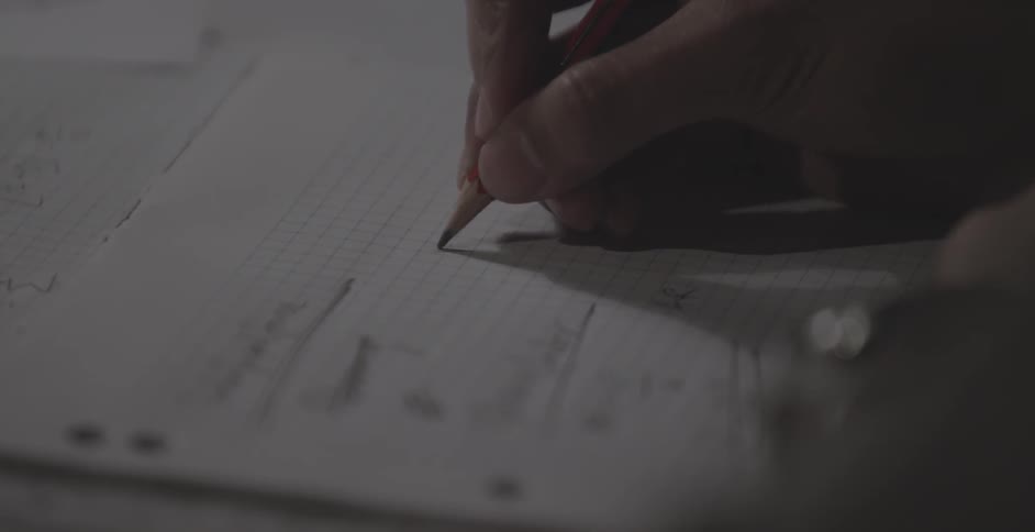 A person makes mathematical notes on graph paper with a pencil