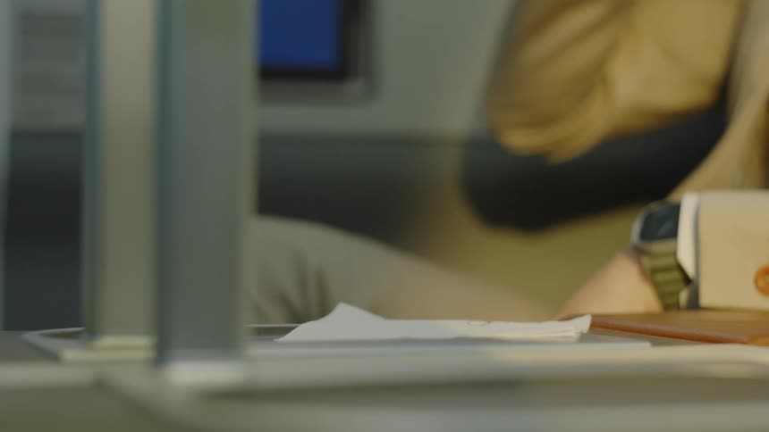 A man in a suit takes a sip from a glass of ice water on a desk