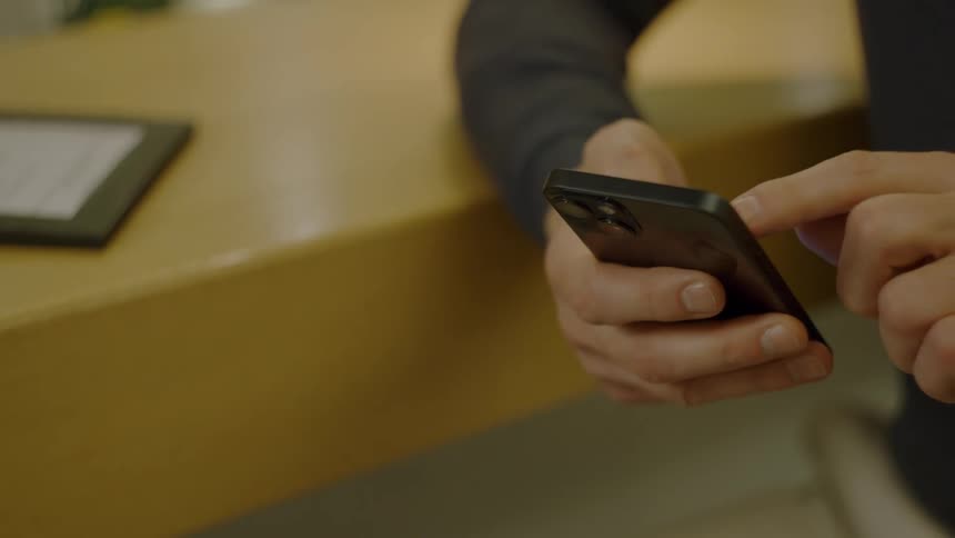 Person using a smartphone over a light wooden counter