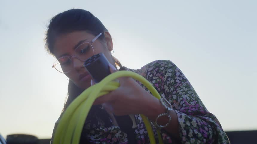 A woman winding a cable outdoors