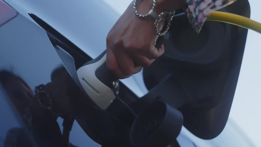 A person plugs a charger into an electric car