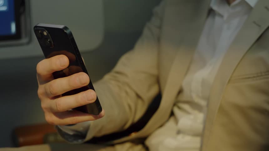Man in a suit holding a smartphone while looking at the screen