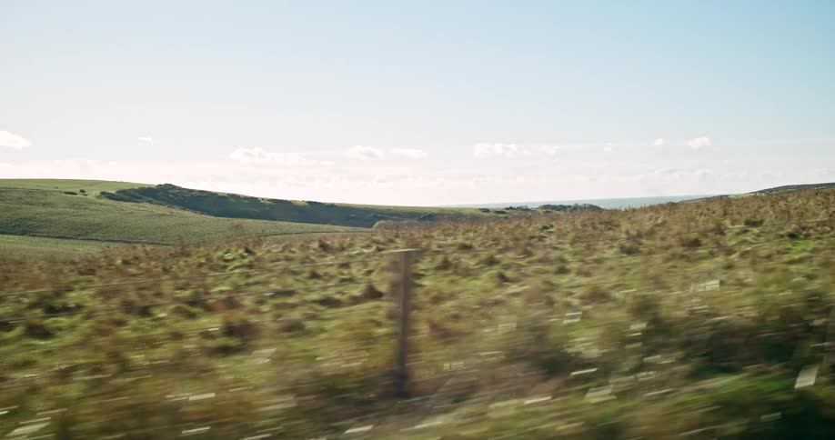 Country fence on the roadside with grass and plants on rural hills and fields