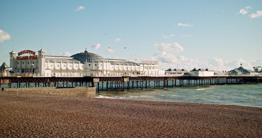 Brighton pier extends over the sea with metal framework and a domed decorative building on a bright day