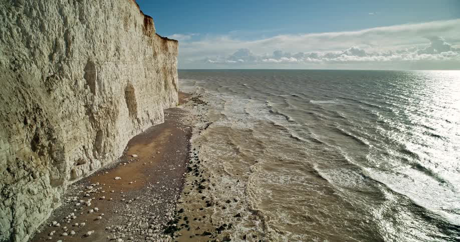 A view of the coast with water reaching the cliffs on a bright day