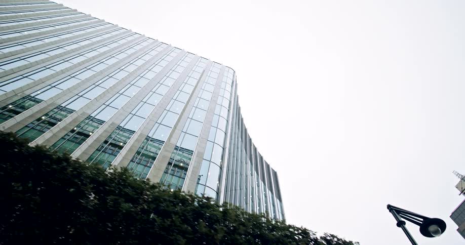 worm's eye view of a Modern glass building reflecting the overcast sky