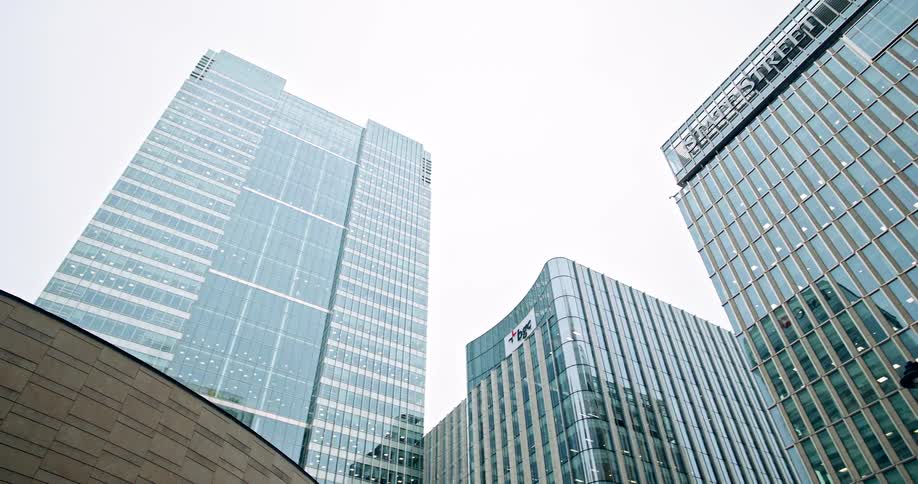 Glass skyscrapers reflecting the overcast sky in a modern financial district