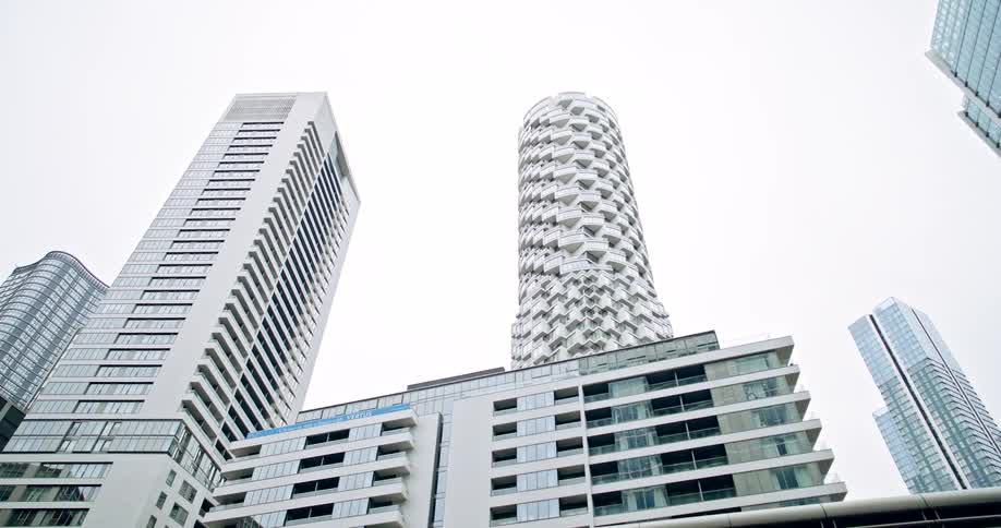 A lowangle shot looks up at a cluster of tall modern white skyscrapers against an overcast sky