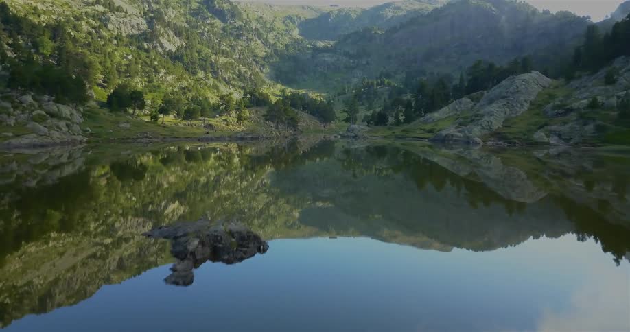 Aerial view moving just above the surface of a lake moving towards some mountains