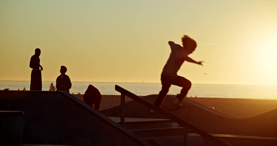 Skater sliding on a rail at sunset with the sea in the background