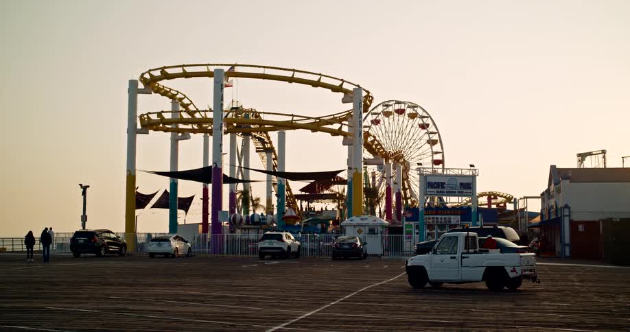 Seaside amusement park with a ferris wheel and roller coaster at sunset