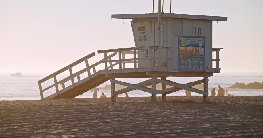 Several people are at the beach near to a lifeguard station