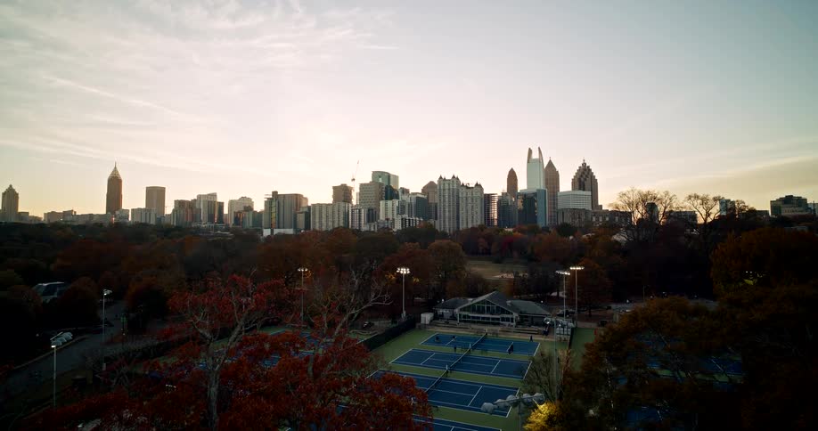 Tennis courts lit at dusk with skyscrapers in the background