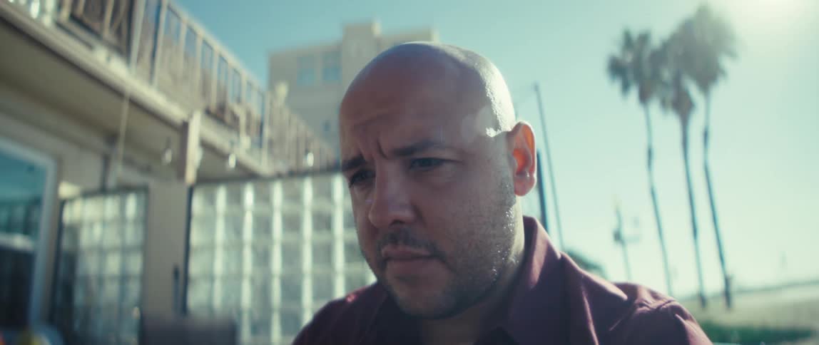 A man sits outside on a sunny day while concentrating on reading
