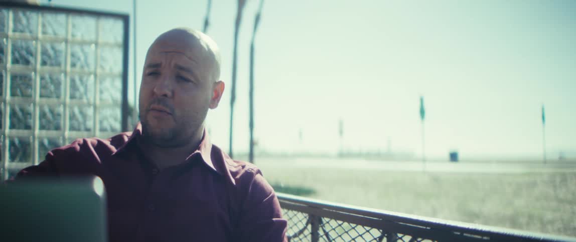 Man using a laptop outdoors near the beach on a sunny day