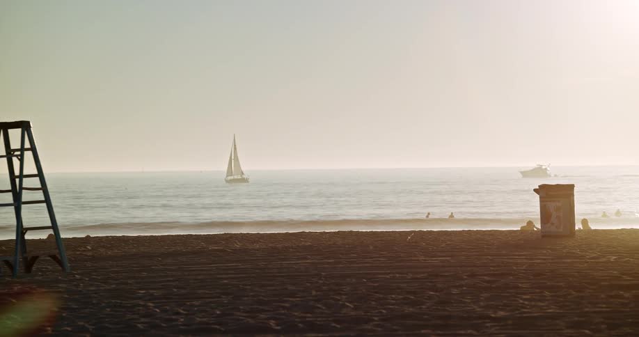 Boats are on the ocean near a beach where people are relaxing