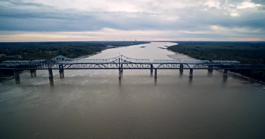 A bridge spans a wide river and connects two forested areas