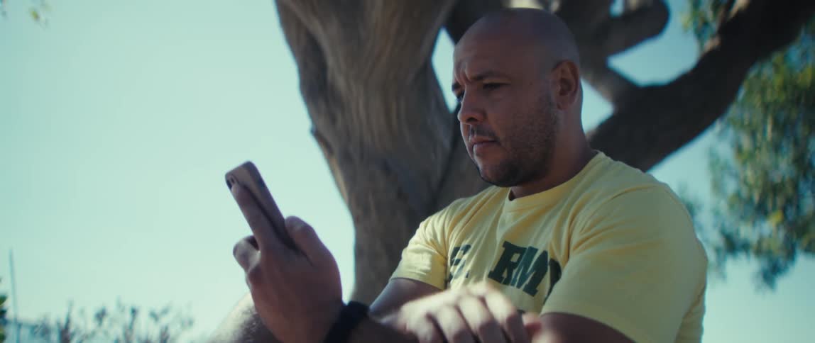 Close up of a man using a mobile phone while sitting outdoors during daytime