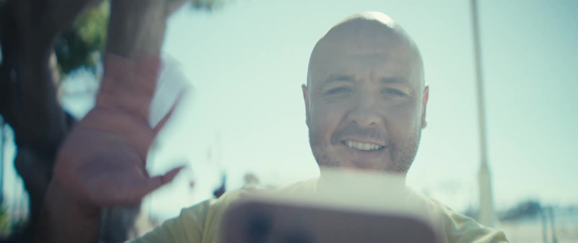 Smiling man waving during a video call outdoors