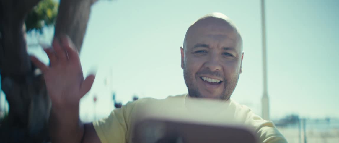 The man smiles and waves at his phone