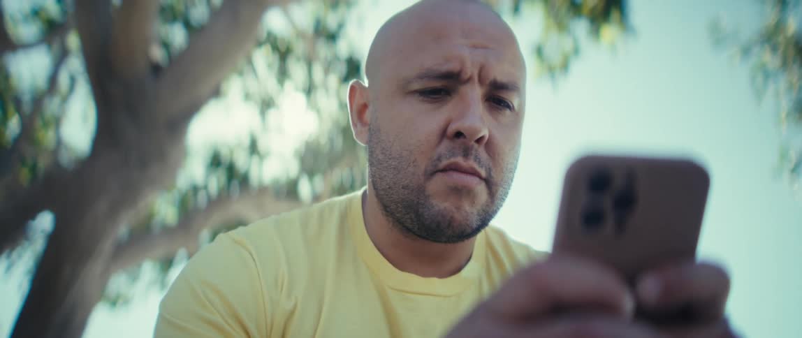 Man near a tree texting on his phone