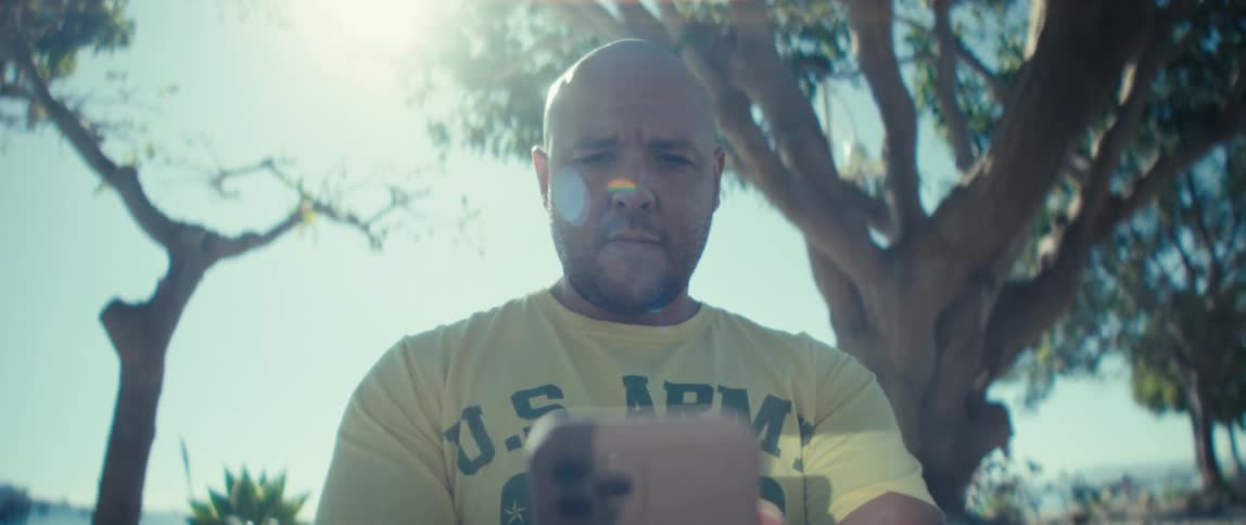 Man looking at his phone under sunlight wearing a us army shirt