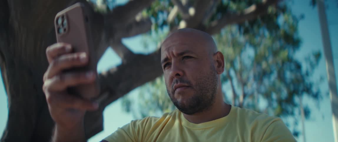 Man wearing a yellow us army veteran shirt holding a phone outdoors