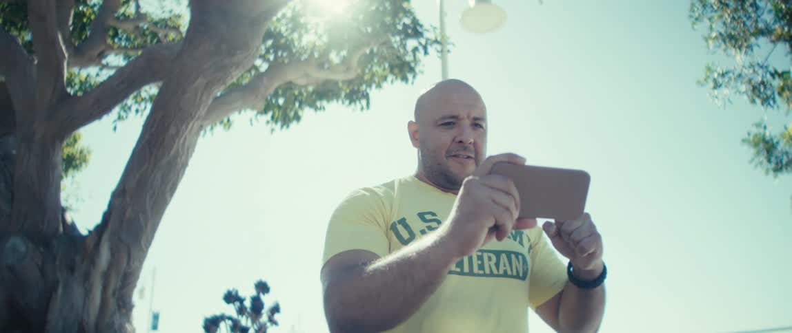 A man outdoors reading information on his phone and cheering