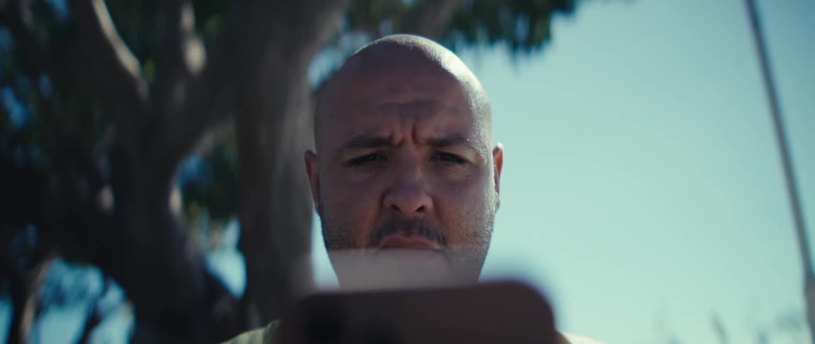 A man nods as he looks at a tablet while sitting outside