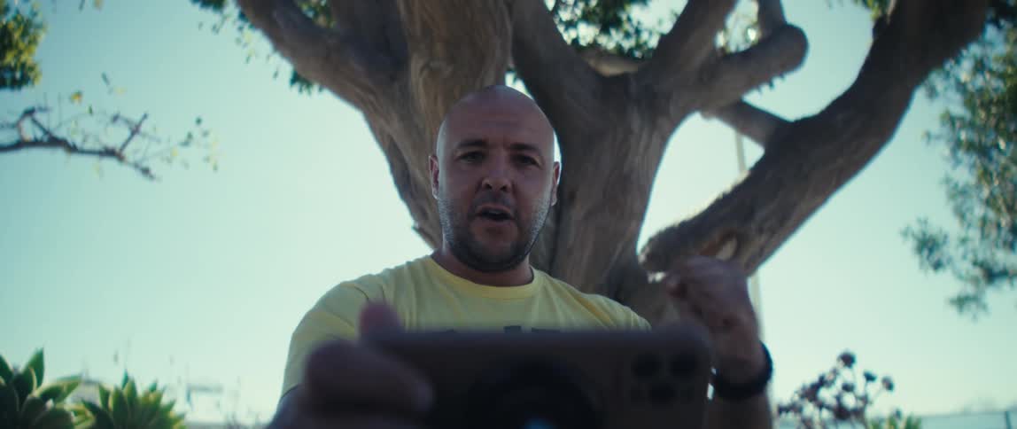 A man is cheering and pumping his fist in the air as he looks at a tablet