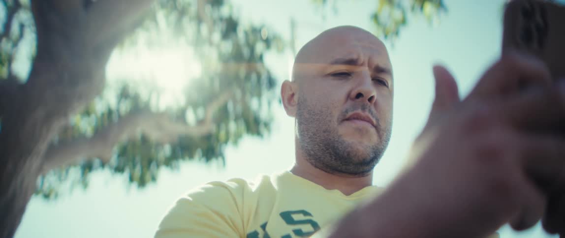 A man looking at a phone outdoors on a sunny day