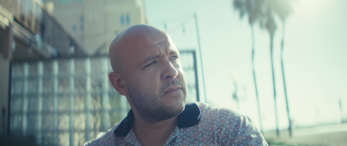 Close up portrait of a man using a laptop computer while sitting at a table outdoors during daytime