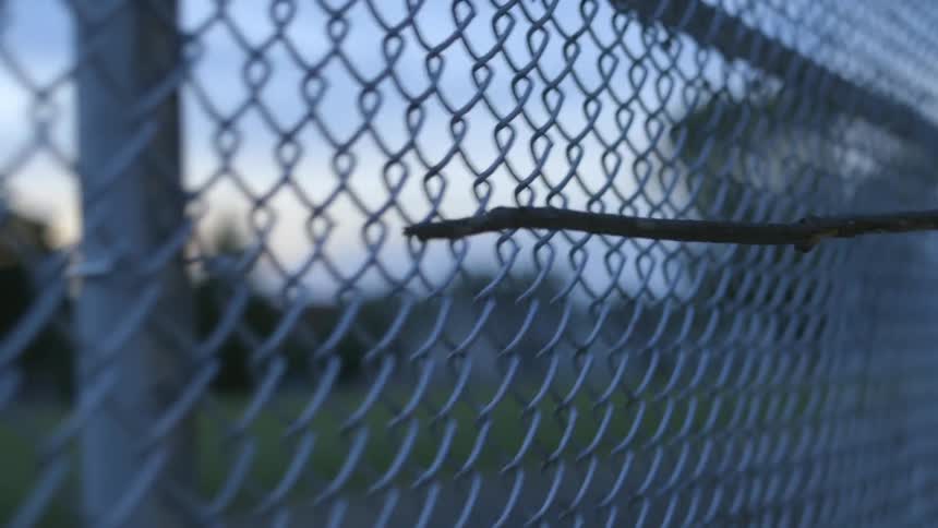 Someone dragging a stick across a chain link fence