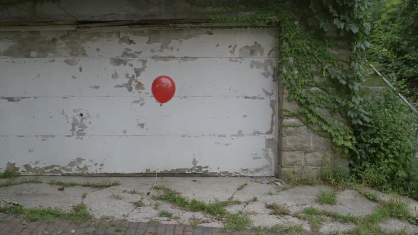 Red balloon floating outside past an old building