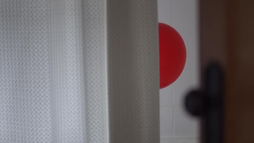 Red balloon floating out from behind a curtain in room