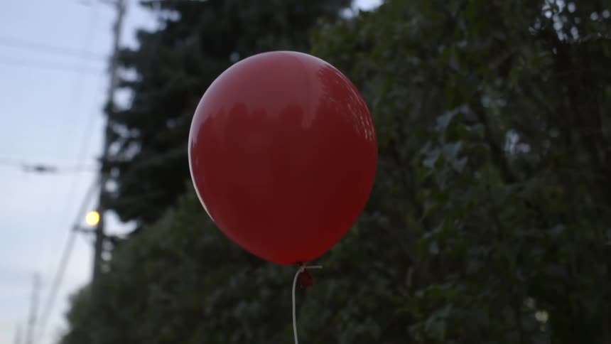 Red balloon floating on a string in a city