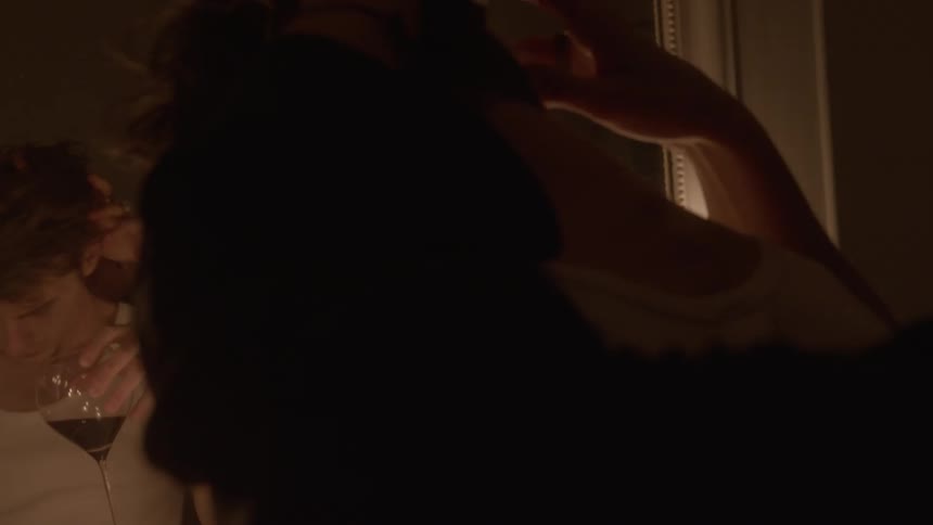 A man and woman are dancing seductively in front of a mirror as they drink wine