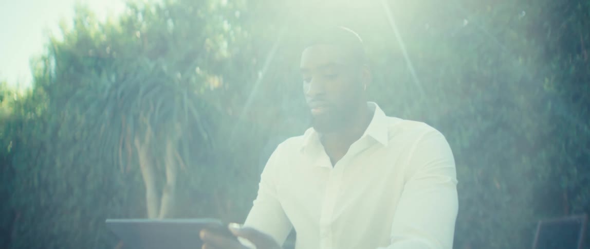 The man smiles and waves at his tablet