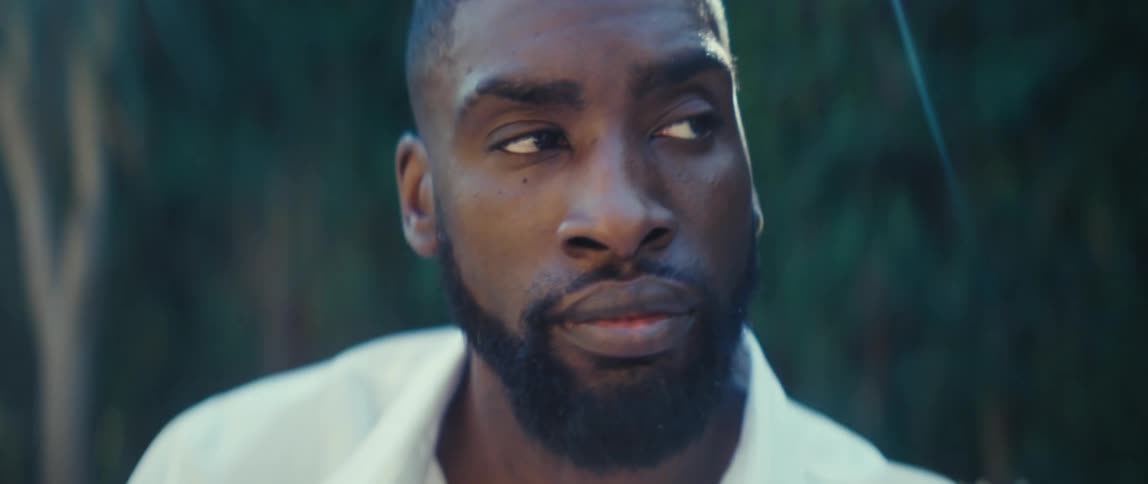 A man with a beard looks up and off to his left while outdoors
