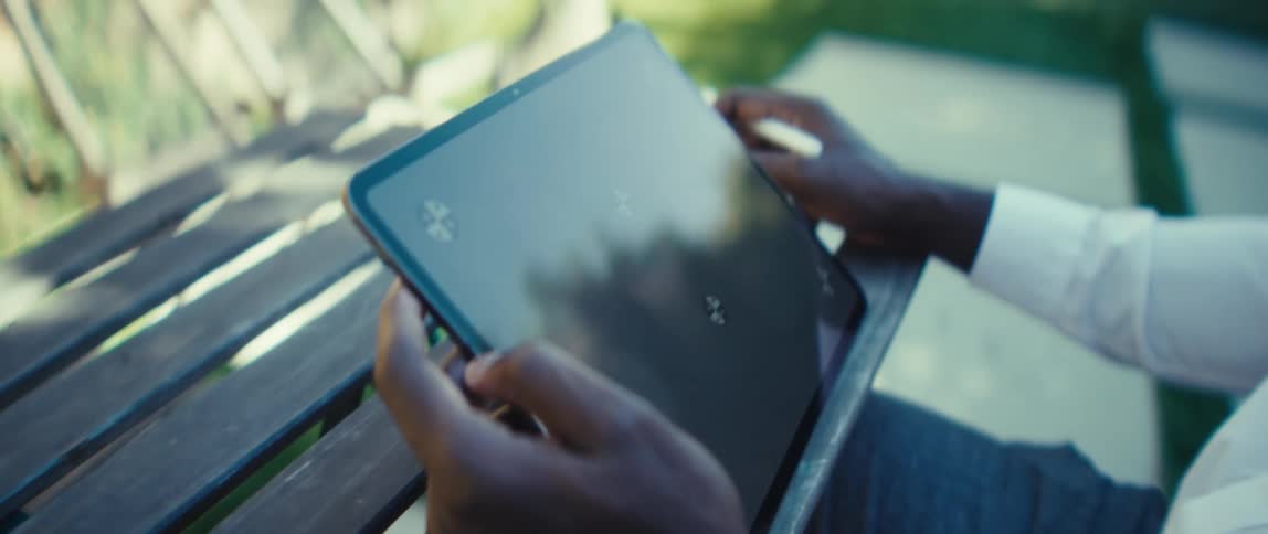 Man holds a tablet computer with a stylus in the other hand as he moves his fingers across the screen